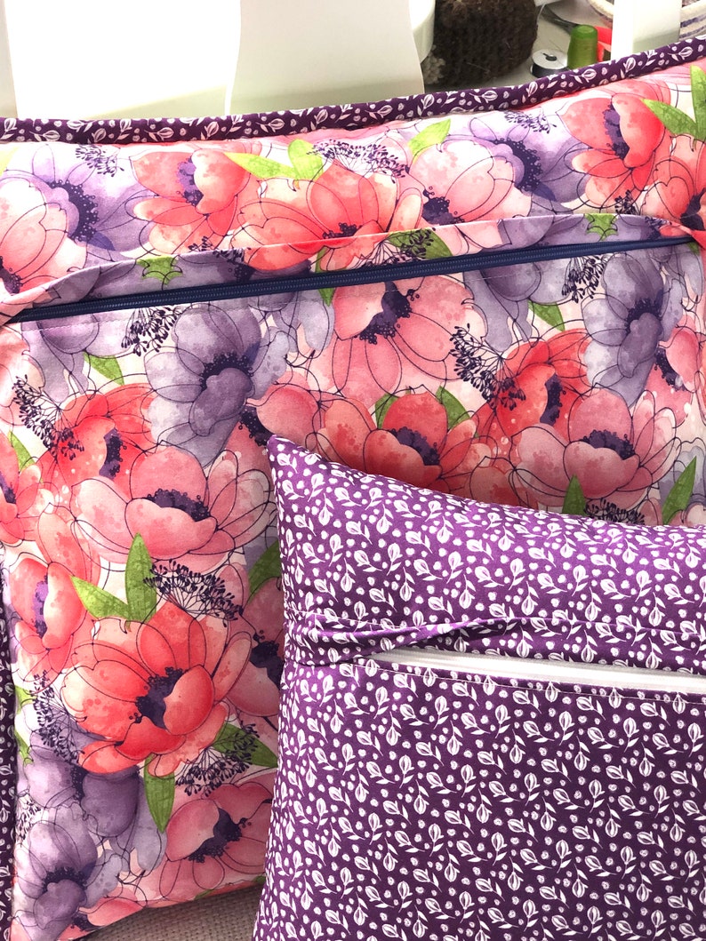 Puede incluir: Dos fundas de coj&iacute;n decorativas con cierres de cremallera. Una funda presenta un patr&oacute;n floral en tonos rosas, morados y verdes. La otra funda tiene un fondo morado con un patr&oacute;n floral blanco.