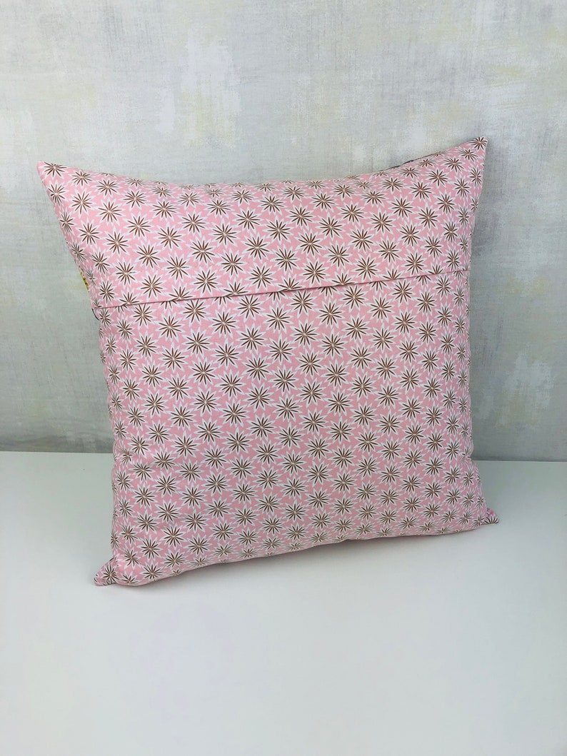 Puede incluir: Una almohada rosa con un patr&oacute;n de estrellas marrones y blancas. La almohada est&aacute; hecha de una tela suave y c&oacute;moda y tiene una cremallera.