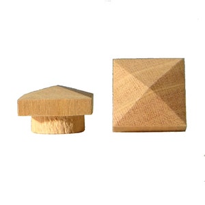 May include: Two wooden pyramid-shaped finials, one with a base and one without. The finials are made of light brown wood and have a smooth finish.