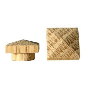 May include: Two wooden finials with a square base and a pyramid-shaped top. The finials are made of light brown wood with a natural grain pattern.