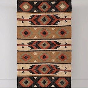 May include: A rectangular woven rug featuring a repeating geometric pattern of diamonds and horizontal bands. The color palette includes shades of black, cream, tan, rust orange, and sage green, arranged in a symmetrical, layered design.