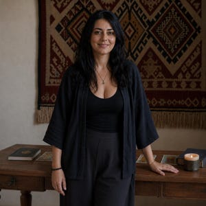 Kathrine, psychic medium and intuitive tarot reader, standing in her reading space with tarot cards, candle and books, offering honest same hour readings written for you