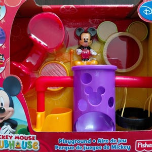 Peut inclure: Un ensemble de jeu de terrain de jeu Disney Mickey Mouse Clubhouse dans une boîte rouge. Le kit comprend une tour violette avec des découpes en forme de Mickey, un toboggan rouge, un siège jaune, une balançoire pneu noire et une figurine Mickey.