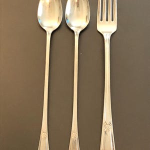 May include: A set of three silver-plated utensils, including two spoons and a fork. The utensils have ornate designs on the handles.