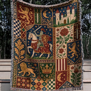Könnte beinhalten: Eine gewebte Wohndecke mit einem mittelalterlich inspirierten Wandteppich-Design, das einen Ritter zu Pferd, eine Burg, Löwen, Kronen, florale Motive und Mondsicheln in Marineblau, Dunkelrot, Gold und Waldgrün zeigt.