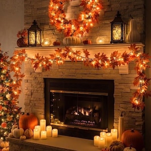 May include: A stone fireplace decorated with an illuminated autumn leaf wreath and garland, featuring warm string lights, various orange and white pumpkins, black metal lanterns, and numerous pillar candles arranged on the hearth and mantel.