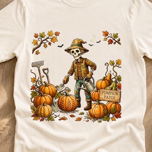 Peut inclure: Un t-shirt couleur crème avec une illustration représentant un squelette portant un chapeau et une chemise à carreaux, tenant un arrosoir dans un champ de citrouilles. Le motif inclut des citrouilles, des outils, des feuilles et PUMPKIN PATCH.