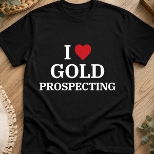 Peut inclure: Un t-shirt noir à manches courtes avec le texte blanc I, un symbole de cœur rouge et le texte blanc GOLD PROSPECTING centré sur la poitrine. Le vêtement présente une encolure ronde et une coupe standard, fabriqué en tissu noir uni.