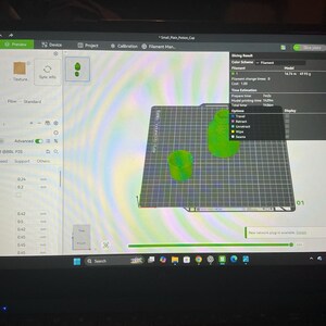 Pode incluir: Uma tela de computador exibindo a interface do software Bambu Studio para impress&atilde;o 3D. A tela mostra uma pr&eacute;via digital de dois modelos de copos verdes em uma placa de constru&ccedil;&atilde;o, juntamente com resultados de fatiamento e configura&ccedil;&otilde;es.