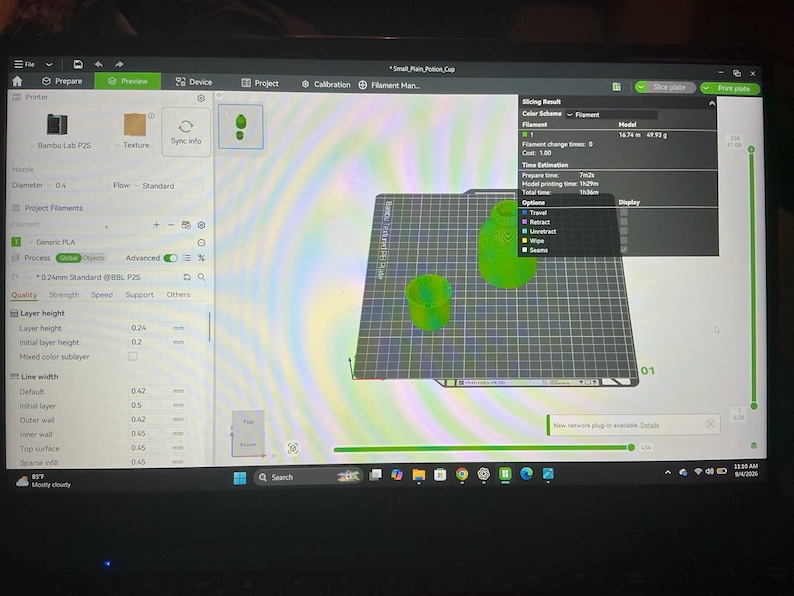Pode incluir: Uma tela de computador exibindo a interface do software Bambu Studio para impress&atilde;o 3D. A tela mostra uma pr&eacute;via digital de dois modelos de copos verdes em uma placa de constru&ccedil;&atilde;o, juntamente com resultados de fatiamento e configura&ccedil;&otilde;es.