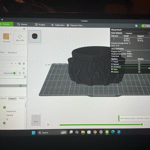 Pode incluir: Uma tela de computador exibindo a interface do software Bambu Studio com um modelo 3D de um caldeir&atilde;o preto em uma placa de constru&ccedil;&atilde;o digital. O software mostra resultados de fatiamento, uso de filamento e tempo estimado de 3h 57m.