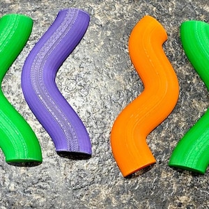 Pode incluir: Uma cole&ccedil;&atilde;o de oito objetos tubulares curvos dispostos em uma fileira. Os itens apresentam uma forma ondulada e serpentina distinta e s&atilde;o coloridos em tons alternados de laranja brilhante, roxo vibrante e verde lim&atilde;o com textura.