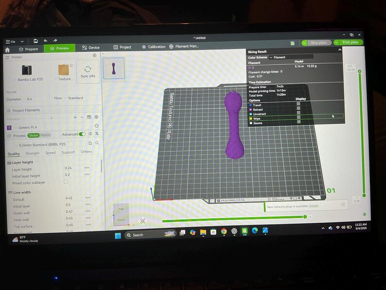 Pode incluir: Uma tela de computador exibindo a interface do software Bambu Studio com um modelo 3D de um objeto roxo em forma de haltere centralizado em uma placa de constru&ccedil;&atilde;o digital. O software mostra um tempo total de impress&atilde;o de 1h 20m.