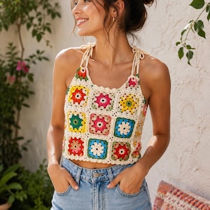 May include: A sleeveless crochet crop top constructed from multi-colored granny squares in shades of red, yellow, pink, green, and blue, joined by cream-colored yarn. The top features thin, adjustable tie-shoulder straps and a scalloped neckline.