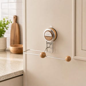 May include: A wall-mounted paper towel holder featuring a circular suction cup base with a light wood and silver metal finish. The horizontal arm is made of silver metal and includes two light wood spherical end caps. The brand name by veil is visible.