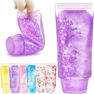 May include: A collection of clear squeeze tubes filled with colorful liquid and various decorative elements. The tubes contain purple glitter with star-shaped sequins, yellow glitter, pink glitter, blue glitter, and fruit-themed confetti pieces.