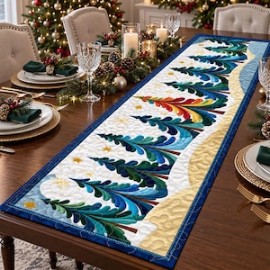 May include: A rectangular quilted table runner featuring a repeating pattern of stylized evergreen trees in shades of blue, green, and a single rainbow-colored tree, set against a white background with gold star accents and a blue border.