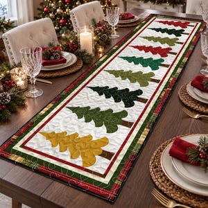 May include: A rectangular quilted table runner featuring a repeating pattern of stylized Christmas trees in red, dark green, olive green, and gold on a white background, bordered by a red, white, and green plaid fabric trim.