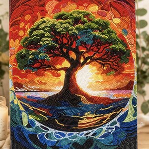 Könnte beinhalten: Ein rechteckiges Diamond-Painting-Set mit einem leuchtenden Baum vor einem kreisförmigen Sonnenuntergangshintergrund. Das Kunstwerk zeigt eine dunkle Baumsilhouette mit grünem Laub über wirbelnden blauen Wassermustern, alles aus bunten Steinchen.