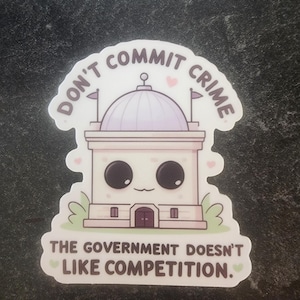 May include: A die-cut sticker featuring a cartoon government building with a light purple dome, large black eyes, and a small mouth. The text reads DON'T COMMIT CRIME at the top and THE GOVERNMENT DOESN'T LIKE COMPETITION at the bottom in brown.