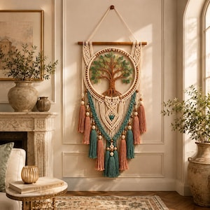 Peut inclure: Une suspension murale en macramé avec un cercle central représentant un arbre tissé en marron et vert. L'objet comprend des nœuds en corde blanc cassé, des pompons bleu sarcelle et vieux rose, et des perles en bois, suspendu à une tige en bois.