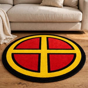 May include: A circular area rug featuring a bold design with a bright yellow cross centred over four red quadrants, all enclosed within a thick black circular border. The rug has a textured surface and is displayed flat on a wooden floor.