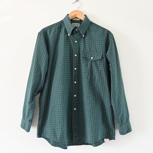 May include: A green and white plaid long-sleeve button-down shirt with a single chest pocket.