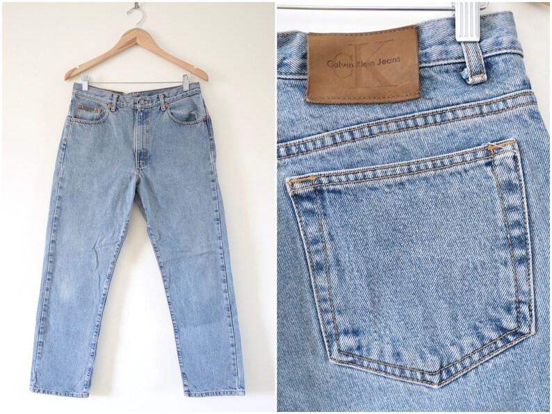Może przedstawiać: Jasne niebieskie dżinsy z brązową sk&oacute;rzaną naszywką z napisem "Calvin Klein Jeans" na tylnej kieszeni.