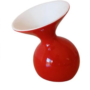 Op de afbeelding: Een glanzende rode vaas met een ronde, bolvormige basis en een brede, uitlopende opening. De binnenkant van de vaas is wit, wat een duidelijk contrast vormt met de felrode buitenkant. Het object heeft een gladde, gebogen vorm en afwerking.