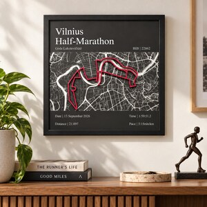 Könnte beinhalten: Ein quadratisches, gerahmtes Wandbild mit einer schwarz-weißen Karte der Strecke des Vilnius-Halbmarathons und einem rot hervorgehobenen Pfad. Der Text enthält den Veranstaltungsnamen, den Namen Goda Lukoševičiūtė, BIB 22862, Datum 13. September 2026, Zeit 1:50:51.2, Distanz 21.097 und Pace 5:15min/km.