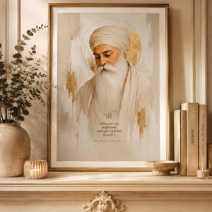 Puede incluir: Una impresión de arte mural vertical enmarcada que presenta un retrato de Guru Nanak Dev Ji en una paleta de colores crema y dorado. La obra muestra una figura con barba y turbante blancos, un halo dorado y el texto SRI GURU NANAK DEV JI.