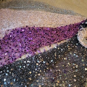 Peut inclure: Un ensemble de trois châles triangulaires dotés d'une structure en maille ajourée ornée de sequins réfléchissants. Les châles sont présentés dans des tons noir, violet profond et champagne métallique clair, chacun terminé par des franges.