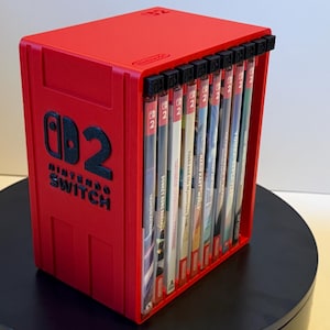 May include: A bright red plastic storage case for Nintendo Switch game cartridges. The side features a black embossed Nintendo Switch logo and the number 2. The case holds ten game cases arranged vertically with black top edges visible.