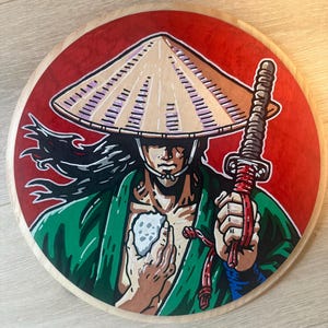 May include: A circular wooden wall art piece featuring a painted illustration of a figure wearing a tan conical hat and a green robe. The figure holds a sword with a red handle and a white object in their hands against a solid red background.