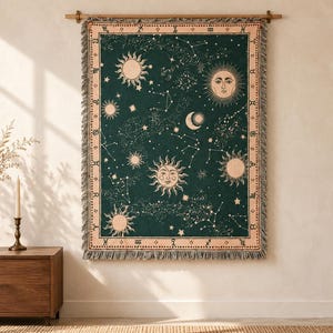 May include: A rectangular woven wall tapestry featuring a dark green background with cream-colored celestial motifs including suns, moons, stars, and constellations. The border displays zodiac symbols, and the edges have a decorative fringe.