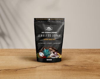 May include: A black stand-up pouch of No Harm Done Jerkless Jerky in Teriyaki Agave Chili flavor. The packaging features white text, a logo with a cow icon, and images of agave, garlic, ginger, and chili peppers. It is labeled 3 oz/85g.