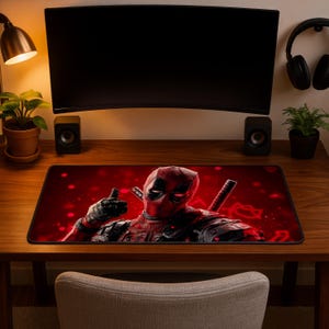 Könnte beinhalten: Eine rechteckige Schreibtischunterlage mit einer grafischen Illustration der Figur Deadpool im rot-schwarzen Anzug, die einen Daumen hoch zeigt. Der Hintergrund ist tiefrot mit verschwommenen Lichteffekten und zwei sichtbaren Katana-Griffen.