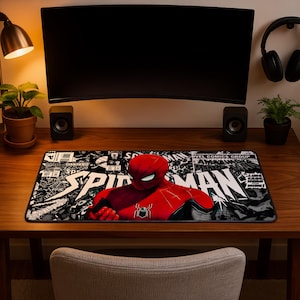 Könnte beinhalten: Eine rechteckige Schreibtischunterlage mit einer zentralen Grafik von Spider-Man in einem rot-schwarzen Anzug. Der Hintergrund besteht aus einer schwarz-weißen Comic-Collage, auf der der Text Spider-Man in großen weißen Buchstaben zu sehen ist.