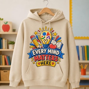 May include: A beige hooded sweatshirt featuring a colourful graphic print of a lightbulb, a pencil, an open book, and a heart. The text reads "EVERY MIND MATTERS HERE" in bold, multi-coloured letters, surrounded by yellow stars and blue accents.