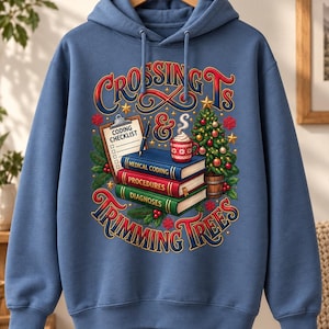 Pode incluir: Uma camisola com capuz azul com uma impressão gráfica com o texto CROSSING TS & TRIMMING TREES. O design inclui uma prancheta com a etiqueta CODING CHECKLIST, uma caneta, uma caneca de cacau e uma pilha de livros intitulados MEDICAL CODING, PROCEDURES e DIAGNOSES.