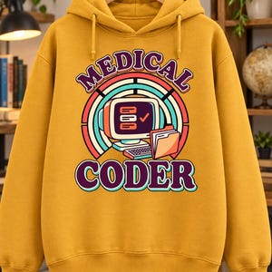 Peut inclure: Un sweat-shirt à capuche jaune moutarde avec une impression graphique portant le texte "MEDICAL CODER" en violet et bleu sarcelle. Le motif comprend un écran d'ordinateur rétro, un clavier et un dossier sur un arc-en-ciel multicolore.