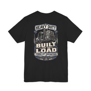 May include: A black short-sleeve t-shirt featuring a graphic on the back of a forklift carrying a crate. The text reads HEAVY DUTY, BUILT FOR THE LOAD, FORKLIFT OPERATORS, and LOAD LIFT MOVE in white and blue lettering against a dark background.