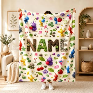 Puede incluir: Una manta de color crema con un patrón repetitivo de coloridos personajes Pikmin, bayas, flores y hojas. La palabra NAME aparece en el centro, con cada letra diseñada para parecer elementos naturales como madera, hojas y piedras.