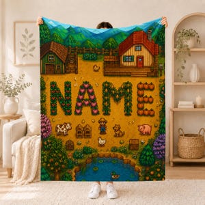 May include: A rectangular fleece blanket featuring a pixelated farm scene with a house, barn, pond, and animals. The word NAME is displayed in the center, formed by pixelated crops including red fruits, green vines, and orange pumpkins on a field.