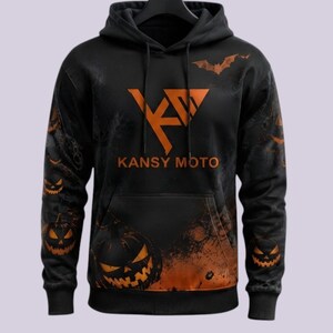 May include: A black hooded sweatshirt featuring an orange graphic logo with the text KANSY MOTO. The design includes orange jack-o'-lanterns, a bat silhouette, and a dark, smoky background pattern across the front and sleeves with a front pocket.
