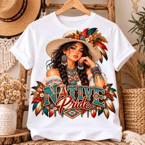 Puede incluir: Una camiseta blanca con un estampado gráfico de una persona con un sombrero de ala ancha adornado con plumas y flores coloridas. La persona tiene el cabello trenzado, joyas de turquesa y el texto "NATIVE PRIDE" impreso en una fuente llamativa.