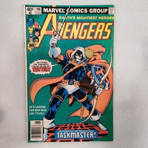 May include: A vintage Marvel Comics Group Avengers issue 196 comic book featuring Taskmaster on the cover. The character wears a white skull mask, blue and orange suit, and cape, holding a sword and bow. Text includes "Anything the Avengers can do, I can do better!" and "Introducing the treacherous Taskmaster!"