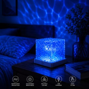 May include: A square-shaped crystal lamp with a textured surface that emits a blue light, creating a water wave projection effect. The base is white and features a power button. Icons below indicate water wave projection, adjustable brightness, multiple colors, USB powered, and easy to use.