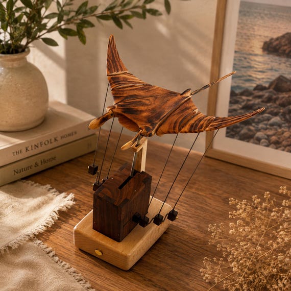 A hand-carved wooden manta ray that actually moves — kinetic mechanical art where the wings undulate like it's gliding through water, made by a real craftsperson.