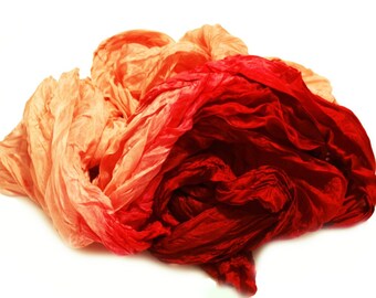 May include: A crumpled piece of fabric in shades of orange and red. The fabric is soft and flowing, with a gradient of color from light orange to deep red.